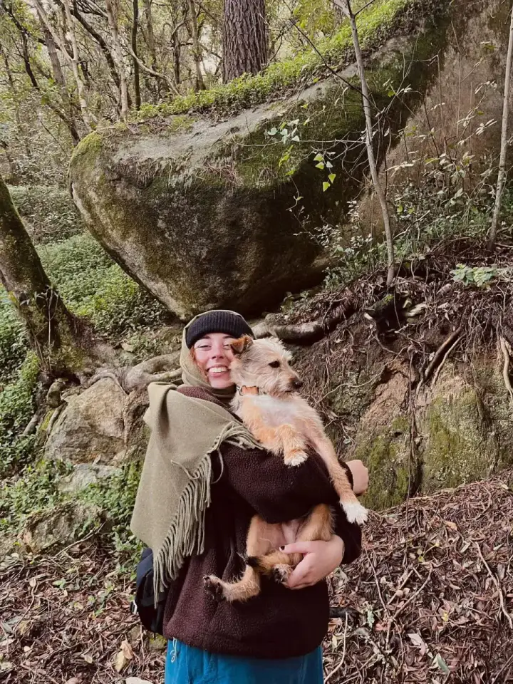 A community member holding her dog during a woodland walk near Mafra